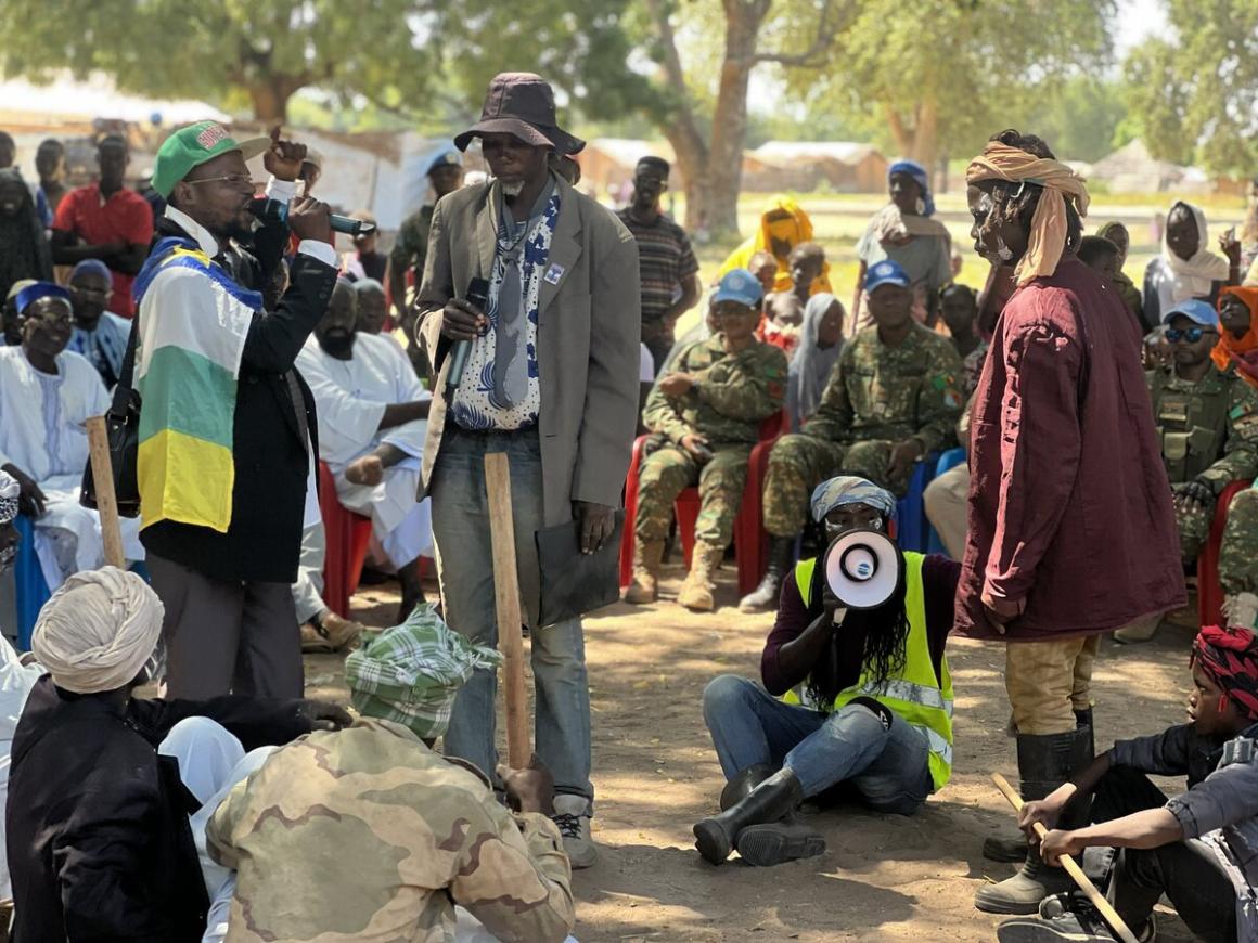 A man sits on the ground holding a megaphone, surrounded by a group of people