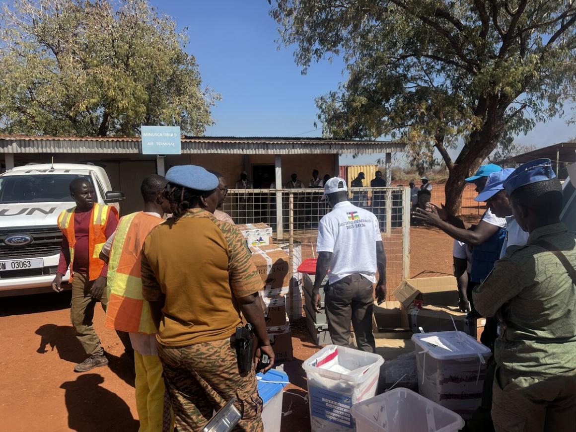Des personnes se tiennent debout avec des cartons contenant du matériel électoral.
